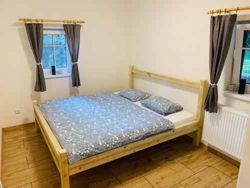 een bed in een kamer met 2 ramen bij Apartmány Jetřichovice - České Švýcarsko in Jetřichovice