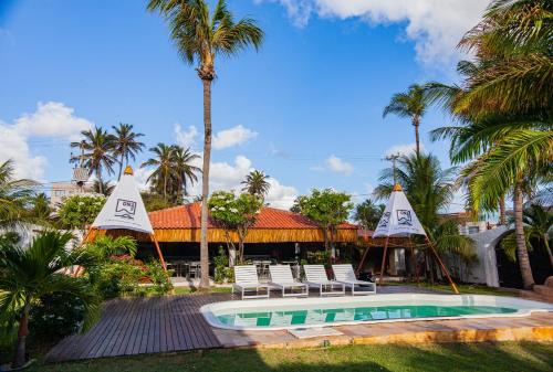 a resort with a pool and chairs and palm trees at Pousada ON VIBE Cumbuco in Cumbuco