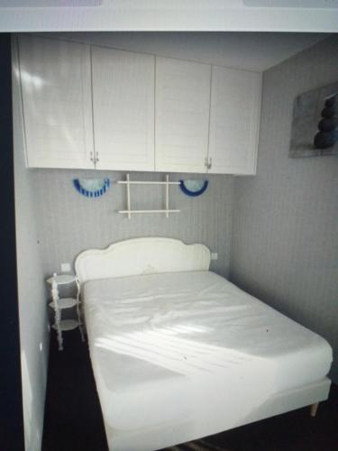 Una cama blanca en una habitación con armarios blancos. en Résidence le plaisance, en Pornichet