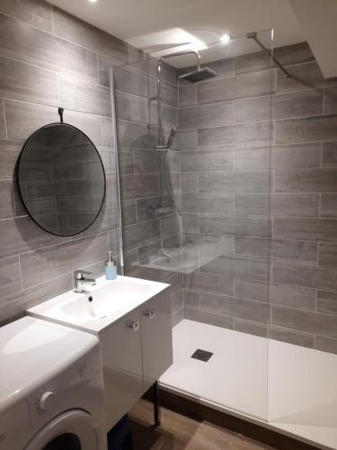 uma casa de banho com um chuveiro, um lavatório e um espelho. em Magnifique appartement face à la mer !! Résidence Charmette em Saint-Hilaire-de-Riez