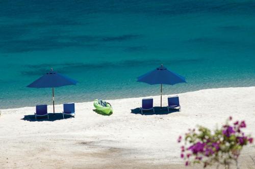 a beach with chairs and umbrellas and the ocean at Rancho Las Cruces in Las Cruces