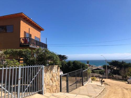 een huis met een hek voor de oceaan bij Hostal F in El Quisco