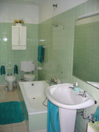 a green tiled bathroom with a sink and a toilet at Casa de São João in Viana do Castelo