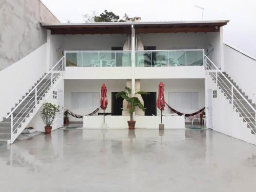 a white building with red umbrellas and plants at A VER O MAR FLATS in Caraguatatuba