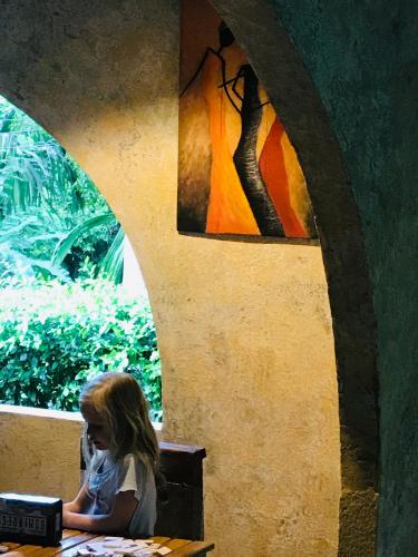 a little girl sitting at a table in front of a window at Finca Carpe Diem Ecolodge in Minca