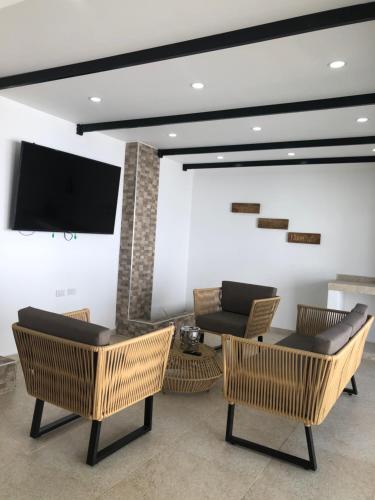 a living room with chairs and a tv on a wall at Casa LOURDES in Valledupar