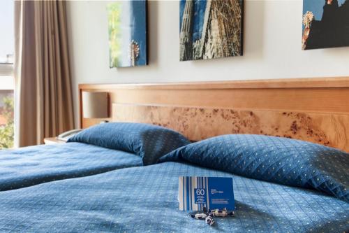 two beds with blue pillows and a book on them at Crisol Quality Reus in Reus
