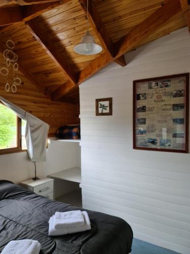 una camera con letto nero e soffitto in legno di Valle Florido a Trevelin