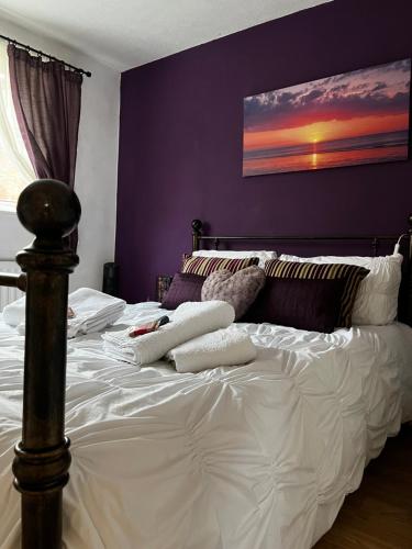 um quarto com uma cama branca e uma parede roxa em Home from home, close to Redditch hospital & transport links em Redditch