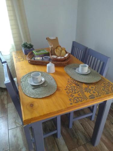 un tavolo di legno con due piatti e tazze e un cestino di pane di Cabañas Tierra del Sol a Las Rabonas