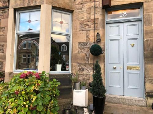 a house with a blue door and a window at Traditional apt close to city centre & Hampden in Glasgow