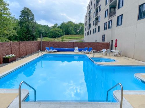 a swimming pool with chairs and a building at Ski-In Ski-out Luxury Condo with Hot Tub and pools in Snowshoe
