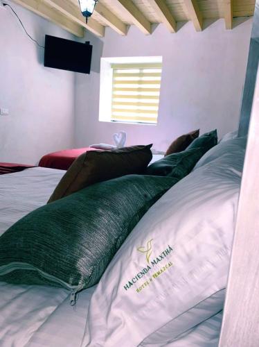 a bed with green pillows in a room at Hotel & Temazcal Hacienda Maxthá in Huichapan