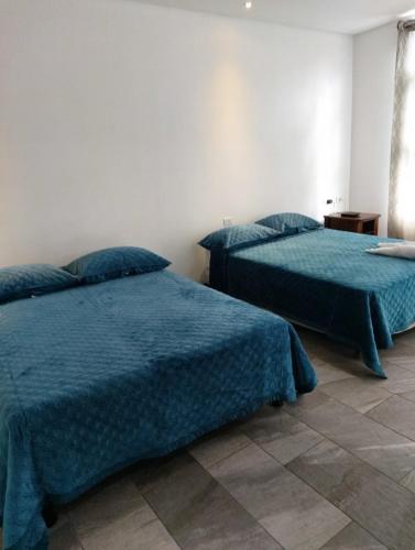 a bedroom with two beds with blue comforters at Pura vida apartments in Quepos