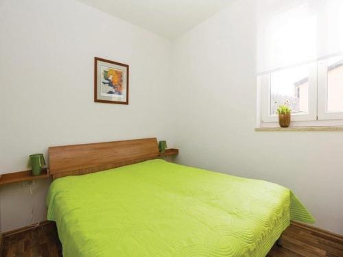 a bedroom with a green bed and a window at Apartments Grzic in Porozina