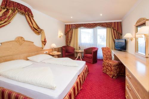 una camera d'albergo con letto, scrivania e sedie di Hotel Jenbacherhof B&B a Jenbach