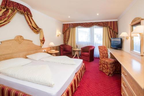 Cette chambre comprend un lit, un bureau et des chaises. dans l'établissement Hotel Jenbacherhof B&B, à Jenbach