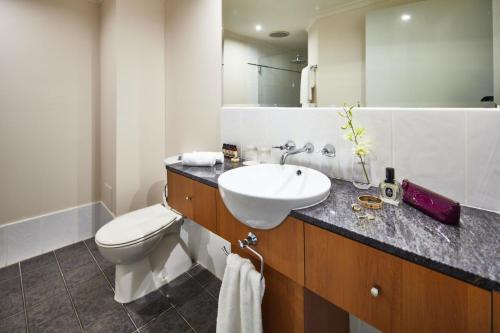 a bathroom with a sink and a toilet and a mirror at Alamanda Palm Cove by Lancemore in Palm Cove