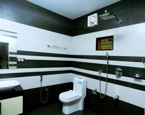 a black and white bathroom with a toilet and a sink at Telma Beach Homestay in Mararikulam