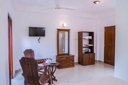 a living room with a table and chairs and a tv at ilamparuma Hotel in Weligama