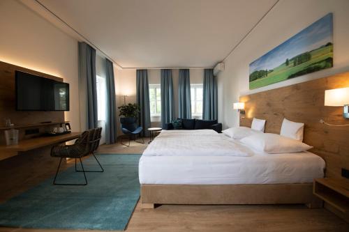 バート・クロイツナハにあるLandhotel Kauzenbergの大型ベッドとテレビが備わるホテルルームです。