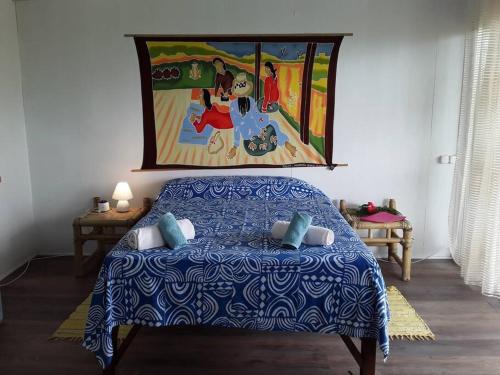 1 dormitorio con 1 cama con una pintura en la pared en SUNSETVIEW, studio, private beach, amazing swim & sunset, en Haapiti