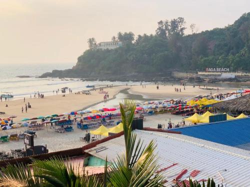 a beach with umbrellas and people on the beach at Baga Beach Sunset in Baga