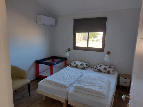 a bedroom with a bed and a window and a chair at בזלת וגיר in Avnei Eitan