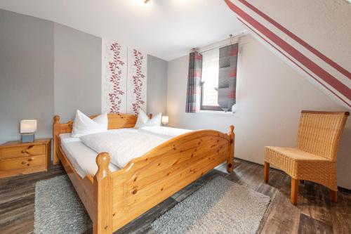 a bedroom with a wooden bed and a chair at Pension Gisela in Gößweinstein