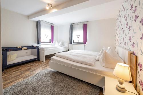 een slaapkamer met een groot wit bed en 2 ramen bij Zweck's Ferienwohnung in Gößweinstein