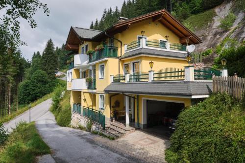 ein gelbes Haus mit Balkon auf einem Hügel in der Unterkunft Landhaus Gabriele in Filzmoos