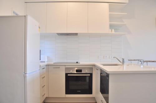 a white kitchen with a sink and a refrigerator at Stunning Townhouse - Walking to Botany Shopping Center in Auckland