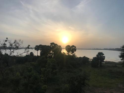 a sunset over a body of water with trees at Arachchi Heritage in Anuradhapura