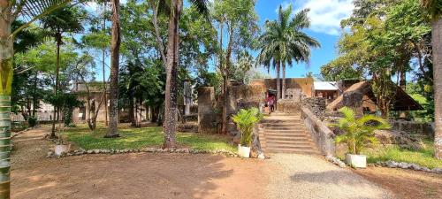 a person walking down a dirt road with palm trees at Mbweni Ruins & Gardens Previously Jungle Paradise in Zanzibar City