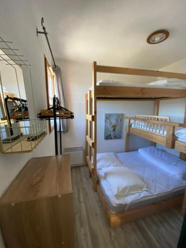 1 Schlafzimmer mit 2 Etagenbetten und einem Holztisch in der Unterkunft Appartement aux pieds des pistes ! in Les Angles
