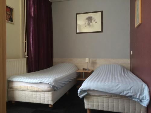 two twin beds in a room with a table at Hotel de Blauwe Vogel in Bergen op Zoom