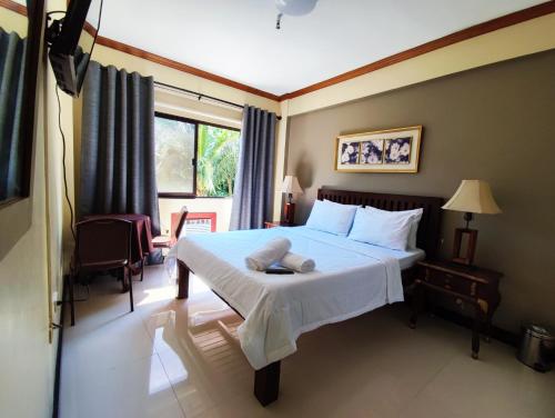 a bedroom with a bed with a white blanket and a window at Spring Plaza Hotel in Dasmariñas