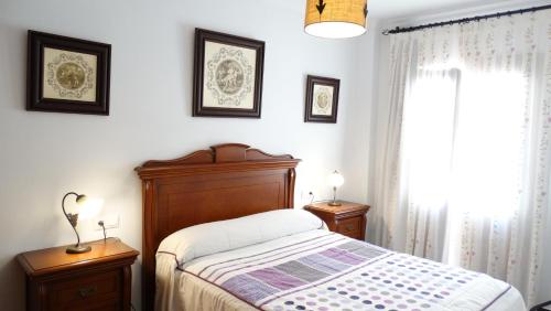 a bedroom with a bed and two night stands and a window at Casa El Campanario del Caminito del Rey in Valle de Abdalagís
