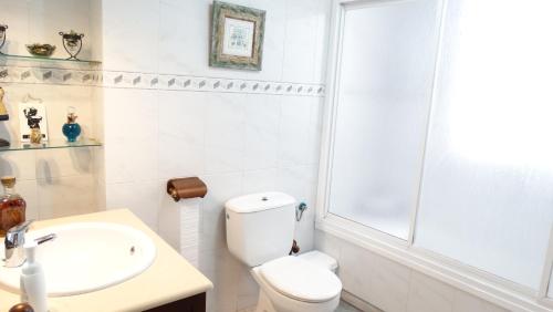 a white bathroom with a toilet and a sink at Casa El Campanario del Caminito del Rey in Valle de Abdalagís