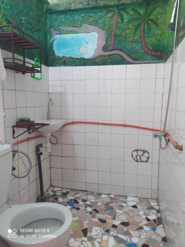 a bathroom with a toilet and a painting on the wall at Chez Yaya - Chambre Brousse in Oussouye