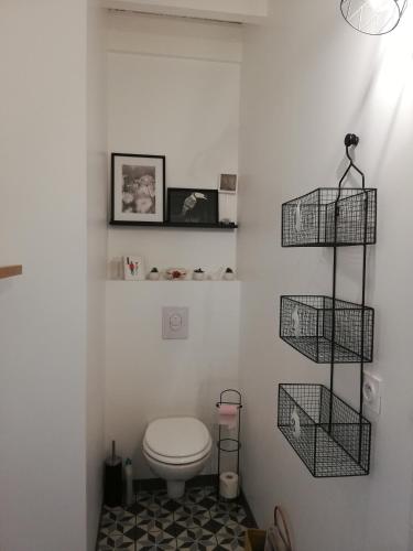 La salle de bains est pourvue de toilettes et de 2 paniers sur le mur. dans l'établissement Chambre d'hôtes Le Cocon des Champs, à Buzet-sur-Baïse