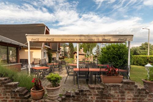 a restaurant with tables and chairs under a pergola at Hotel Zéta in Lenti