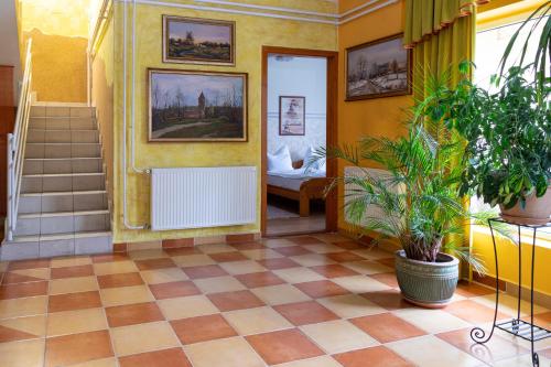 a hallway with yellow walls and a floor with a plant at Hotel Zéta in Lenti