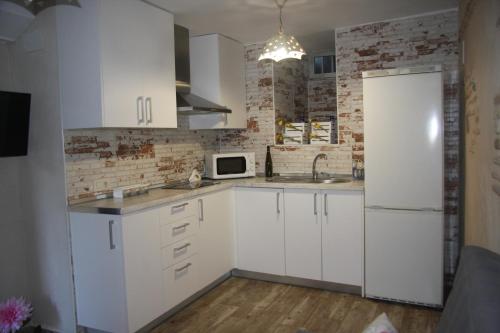 a kitchen with white cabinets and a brick wall at EL EMBARCADERO in Toledo