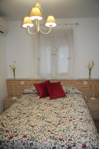 Un dormitorio con una cama con almohadas rojas y una ventana en EL EMBARCADERO en Toledo