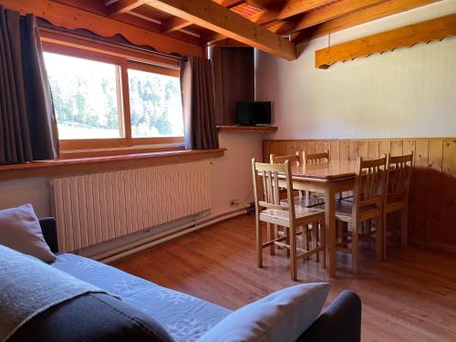 une salle à manger avec une table et des chaises et une fenêtre dans l'établissement LE SAPORTA- Studios et Appartements meublés de tourisme, à Le Lioran