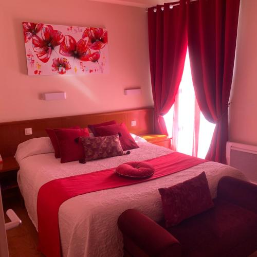 a bedroom with a bed with two red pillows on it at Auberge Du Cheval Blanc in Beaumont-Pied-de-Boeuf
