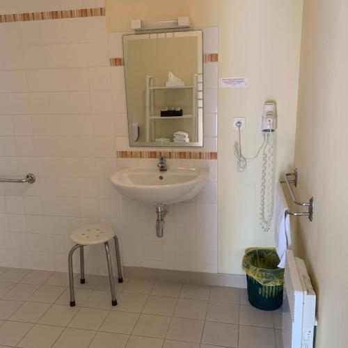 a bathroom with a sink and a stool and a mirror at Auberge Du Cheval Blanc in Beaumont-Pied-de-Boeuf