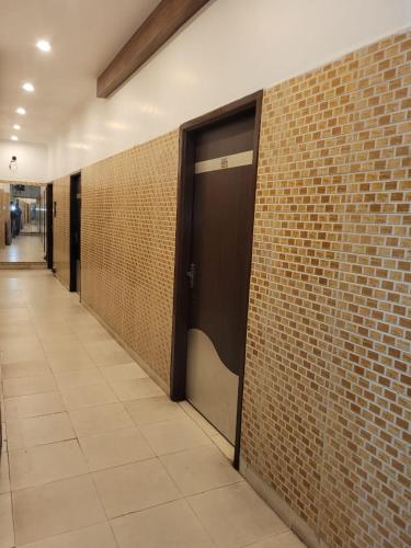 a hallway with a door and a brick wall at Asha Guest House in Amritsar