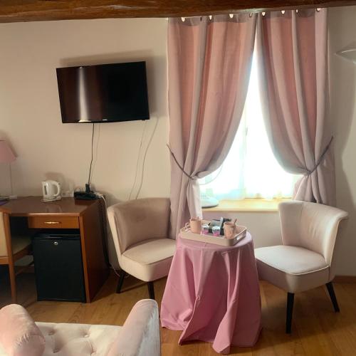a living room with a table and two chairs and a window at Auberge Du Cheval Blanc in Beaumont-Pied-de-Boeuf
